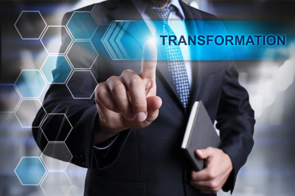 A man in a suit and tie pointing to the word " transform ".